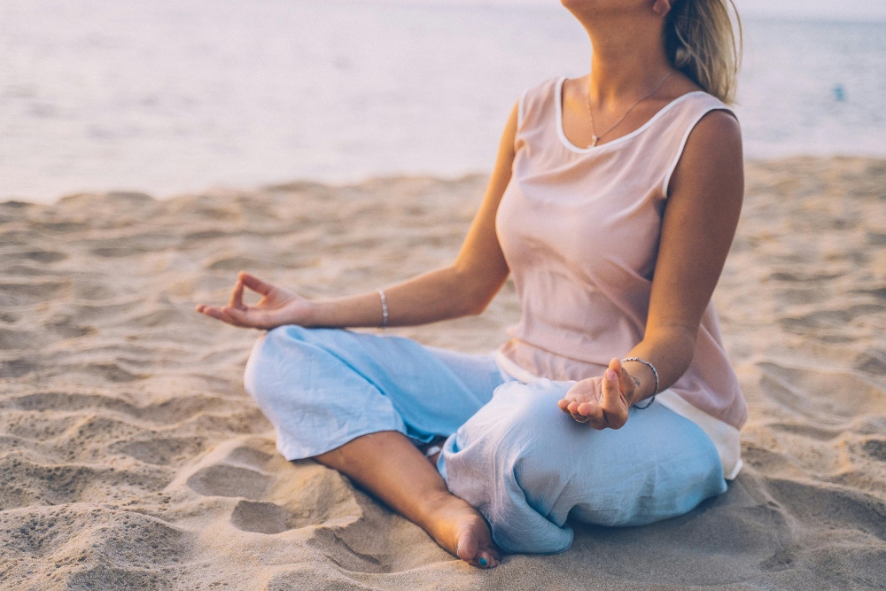 Woman on the beach meditating on the relationship between mental health and addiction.