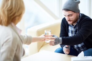 Man taking a glass of water because he isn't sure if he is a high-functioning alcoholic