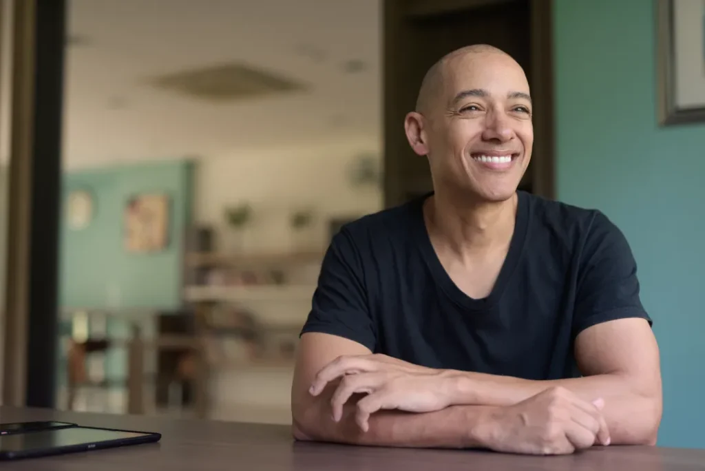 smiling hispanic man in library wearing black | Detox California